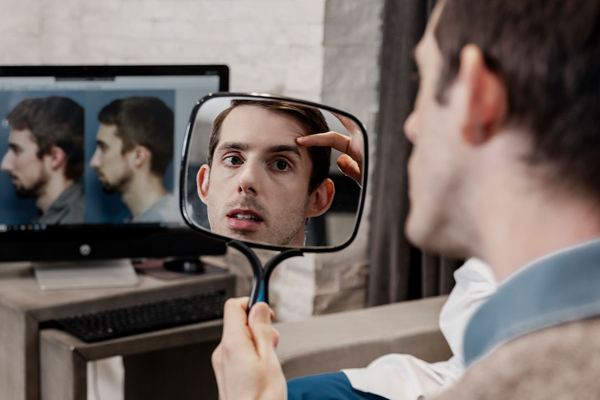 a patient looking at his face in a mirror after a brow lift in Raleigh