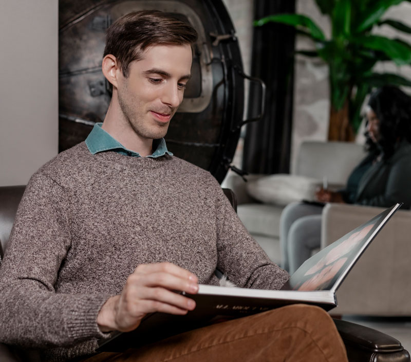 a man looking at a portfolio of before and after images of open rhinoplasty in Raleigh at Stein Plastic Surgery