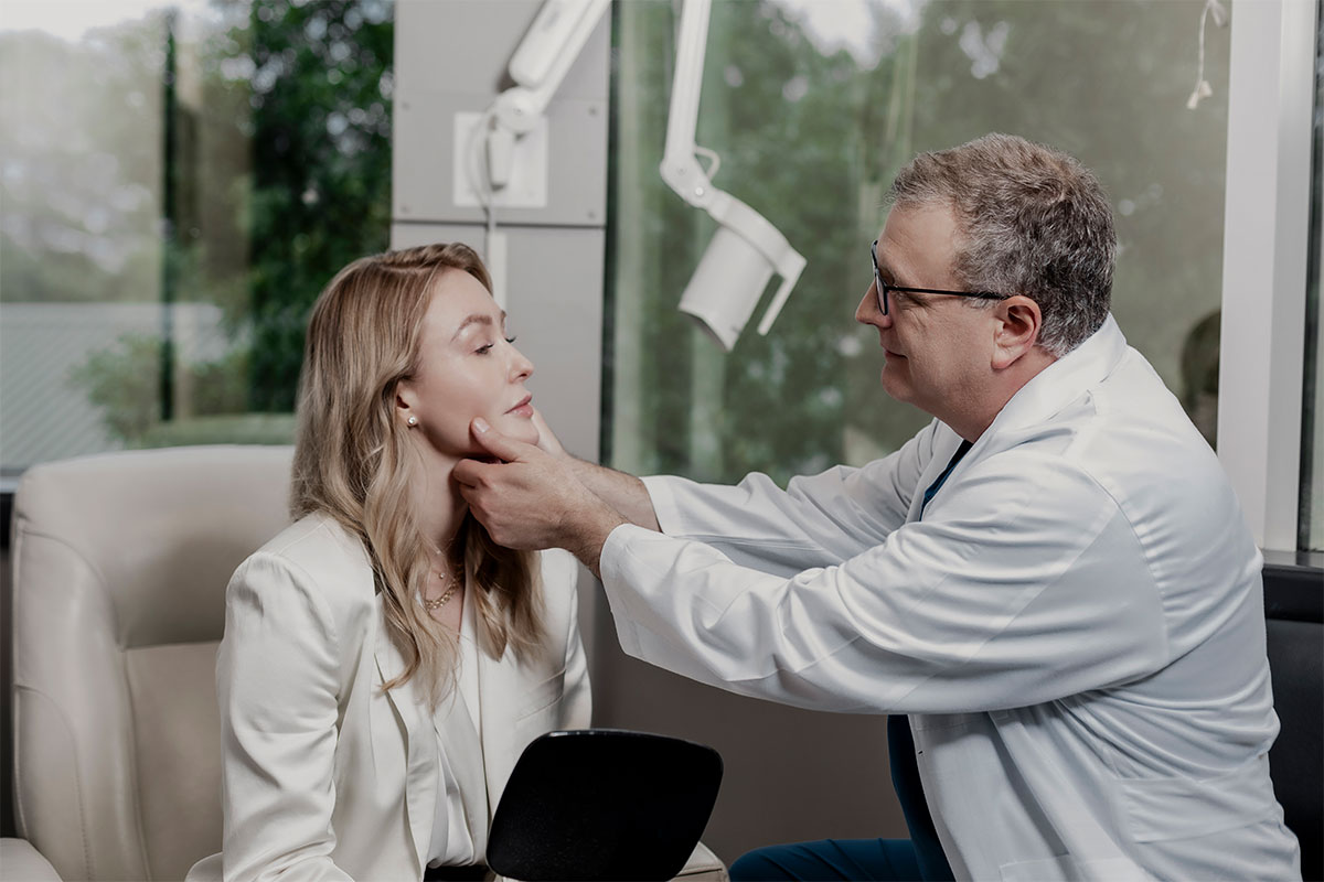 Dr. Stein examines a patients face after a primary facelift in Raleigh